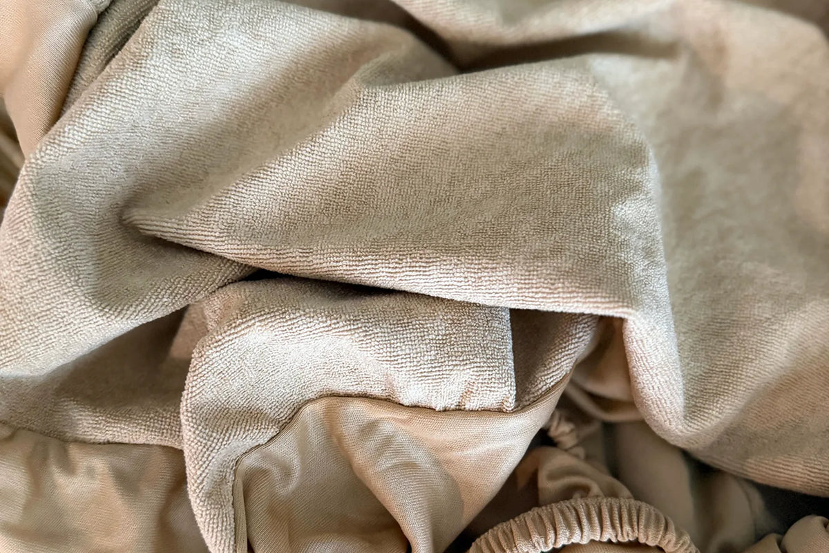 Fitted mattress protector gathered in soft folds, included with the Nurture